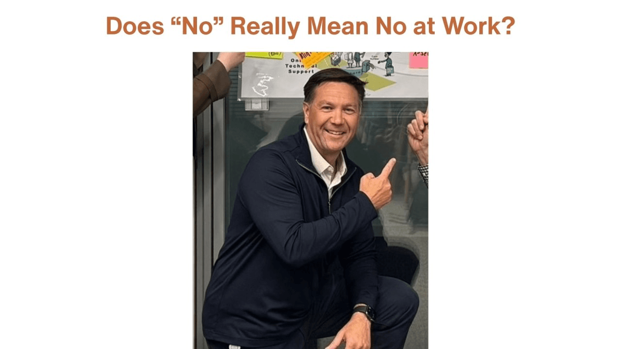 Article cover headed “Does ‘No’ Really Mean No at Work?” in copper type, above a photo of Shawn Slusser crouching beside a glass office wall, smiling and pointing back at a whiteboard sketch about technical support behind him.